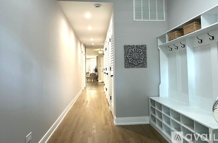 A long hallway with a bench on the side and a door at the end.