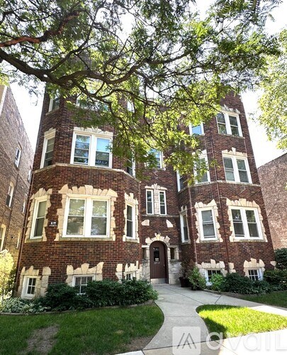 A large red brick house with a tree in front.