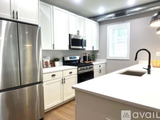 A modern kitchen with white cabinets and stainless steel appliances.