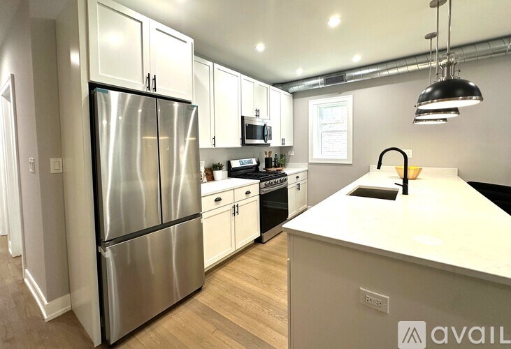 A modern kitchen with a stainless steel refrigerator and white countertops.