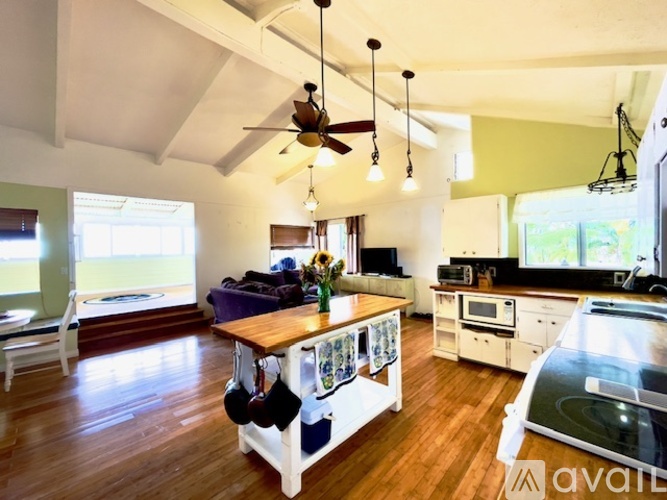 A kitchen with a wooden table and a fan hanging from the ceiling.