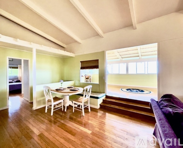 A dining room with a table set for four and a purple couch.