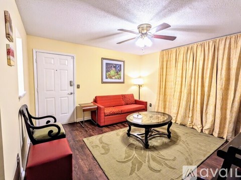 A living room with a red couch and a ceiling fan.