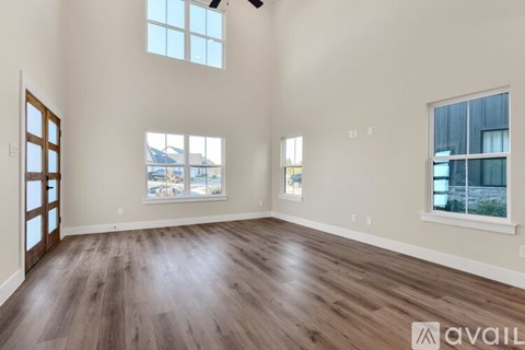A spacious room with wooden floors and large windows.