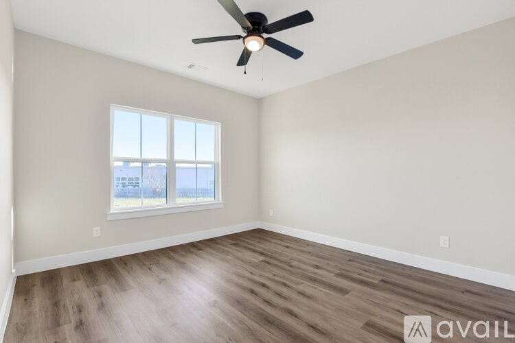 A room with a ceiling fan and a window overlooking a building.