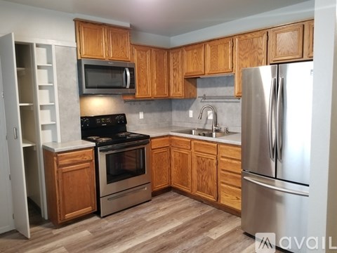 A kitchen with wooden cabinets and a stainless steel refrigerator.