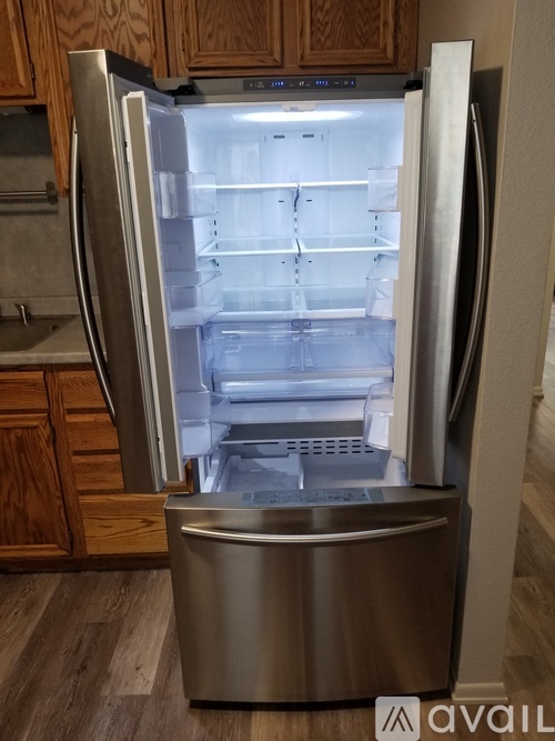 A stainless steel refrigerator with its door open in a kitchen.