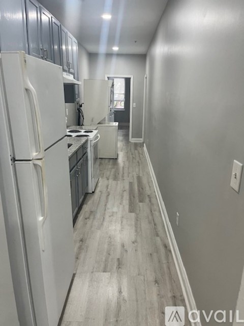 A kitchen with white appliances and wood flooring.