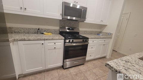 A kitchen with white cabinets and a granite countertop.