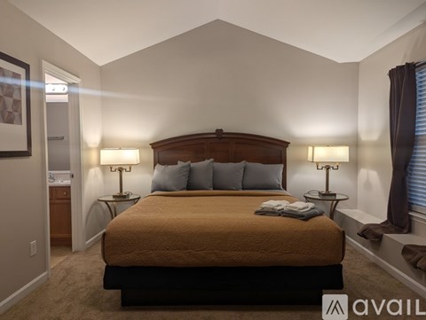 A bedroom with a bed, nightstands, and lamps.