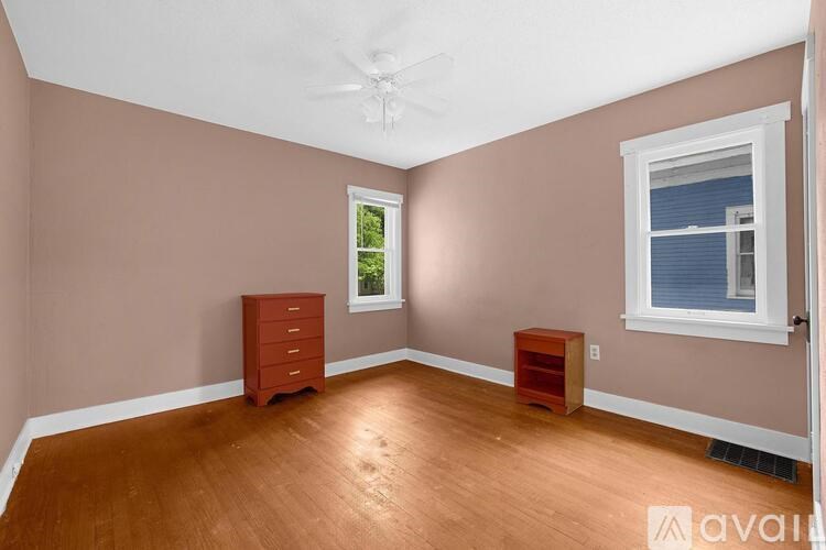 A room with a brown floor and a ceiling fan.