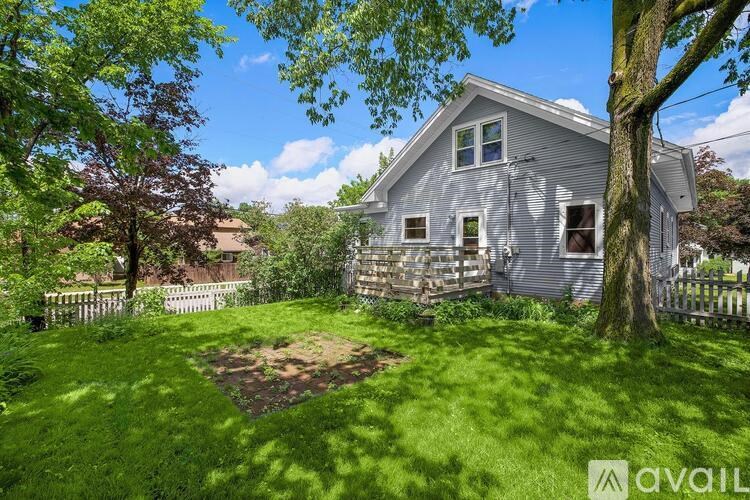 A house with a fence and a tree in front of it.