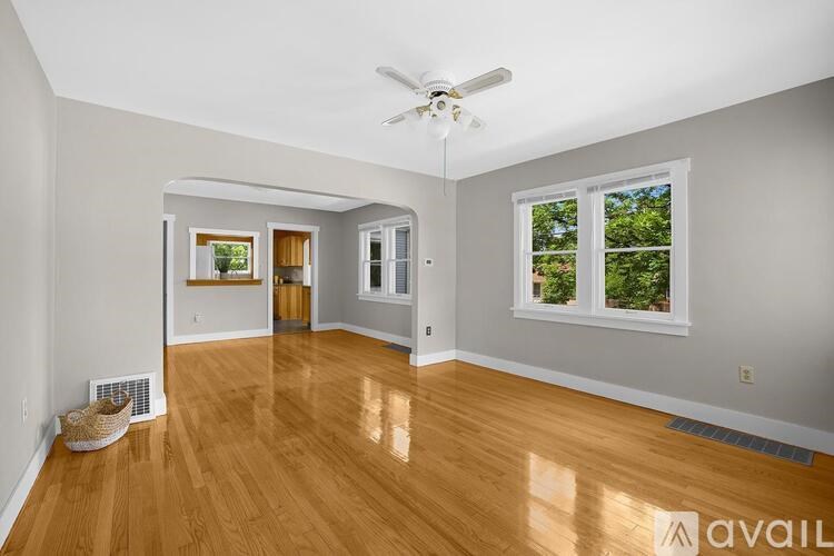 A spacious room with wooden floors and a ceiling fan.