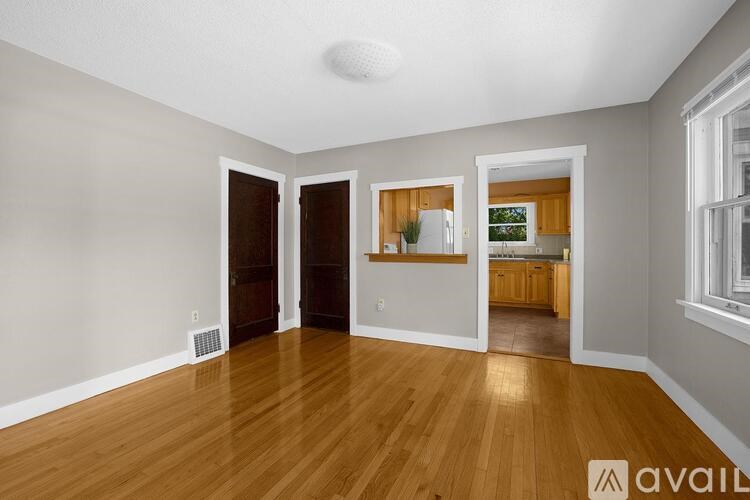A room with wooden floors and a view into a kitchen.