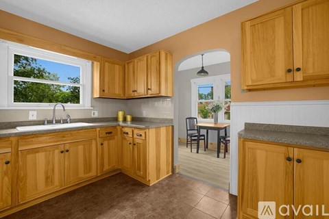 A kitchen with wooden cabinets and a view of trees outside the window.