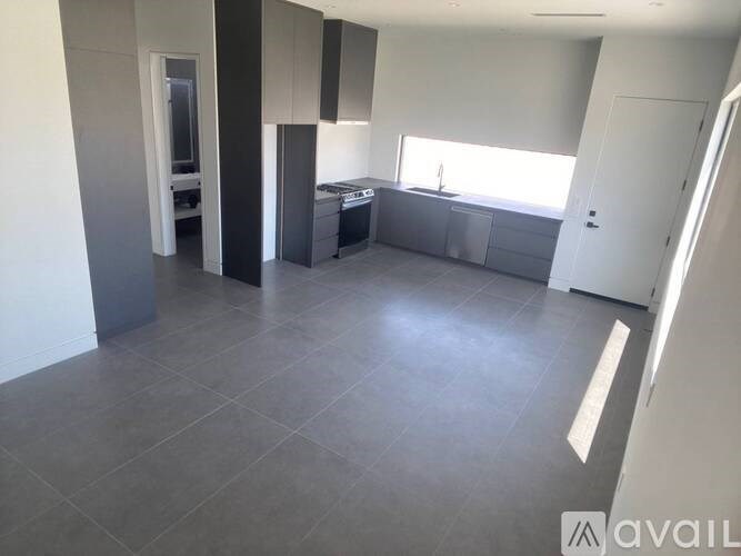 A spacious, empty room with a kitchen area in the background.