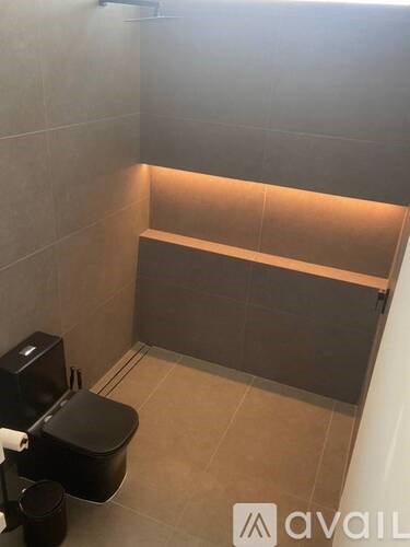 A bathroom with a toilet, a trash can, and a bench.