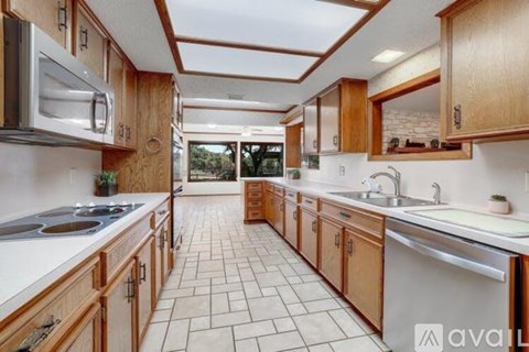 A kitchen with wooden cabinets and a tiled floor.