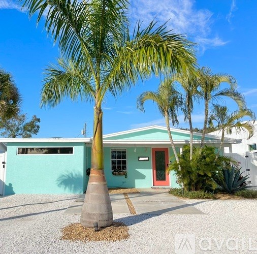 A house with a red door and a palm tree in front.