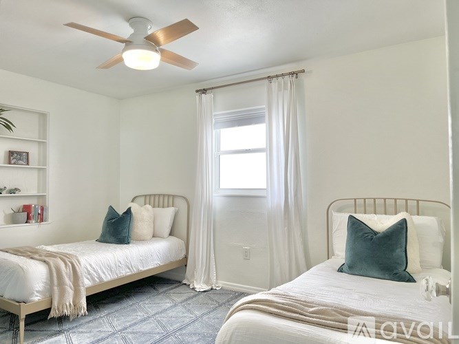 A bedroom with two beds and a ceiling fan.