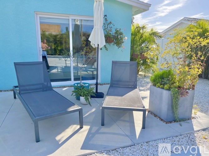 A patio with two chairs and a table with a white umbrella.