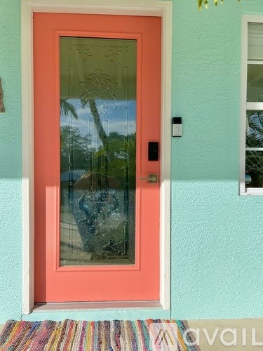 A red door with a glass window and a doormat in front.