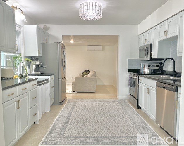 A kitchen with white cabinets and a grey rug on the floor.