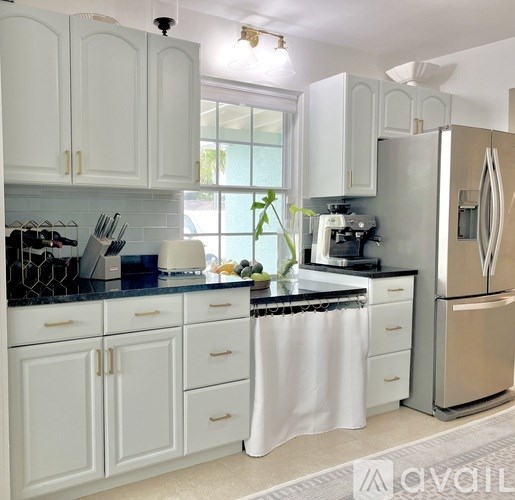 A kitchen with white cabinets and a black countertop.