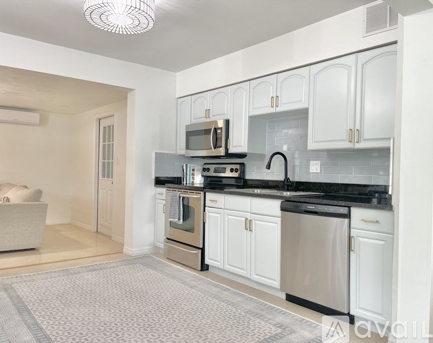 A kitchen with white cabinets and black countertops.
