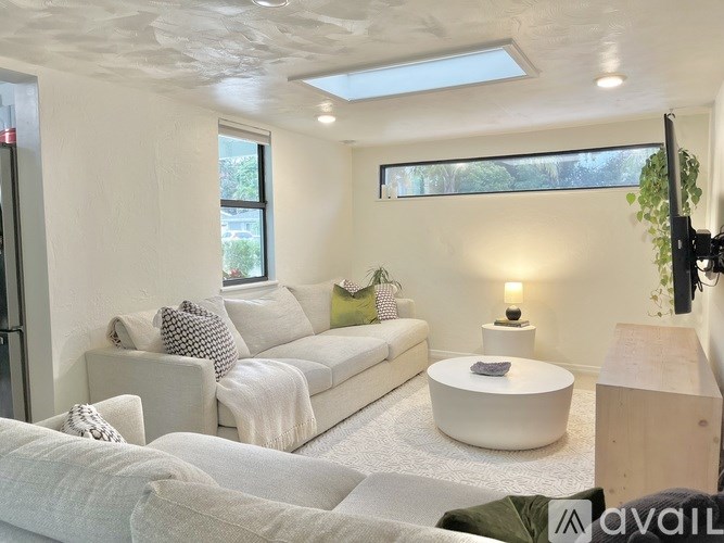 A living room with a white couch and a white ottoman.
