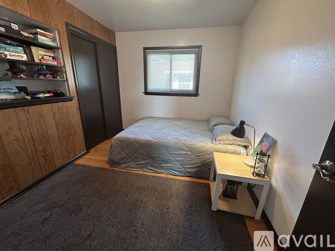 A bedroom with a bed, nightstand, and a window.