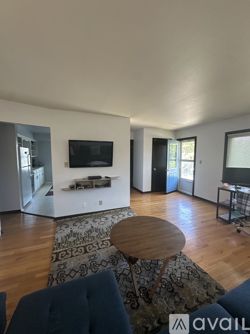 A living room with a television, a rug, and a wooden table.