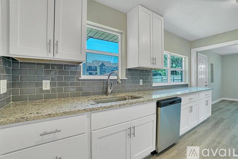 A kitchen with white cabinets and a granite countertop.