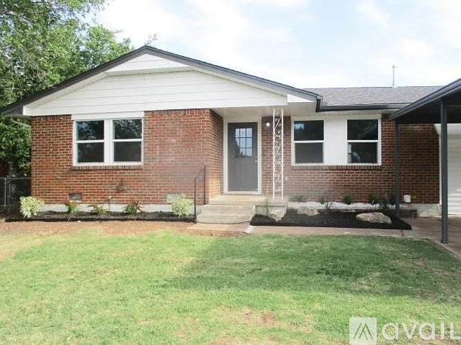 A brick house with a front porch and a green lawn.