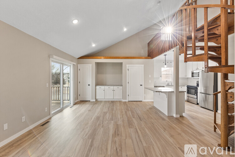 A spacious kitchen with wooden floors and a staircase on the right side.