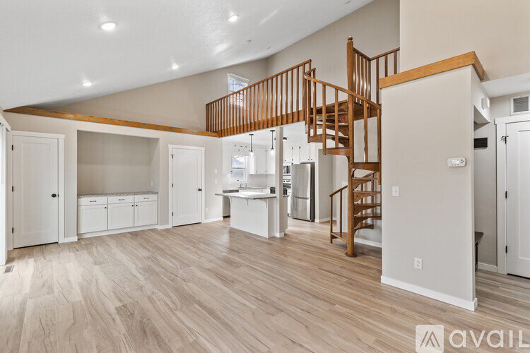 A spacious room with a wooden staircase and white walls.