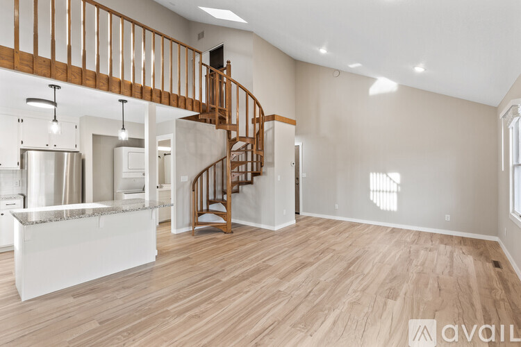 A spacious room with wooden flooring and a staircase.