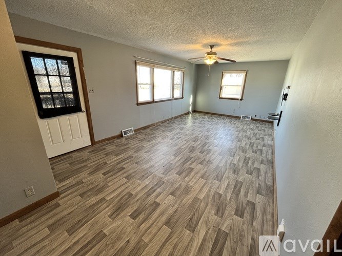 A room with wooden flooring and a ceiling fan.