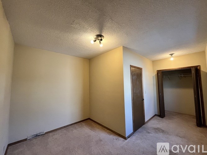A room with a carpeted floor and a door on the left side.