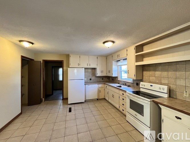 A kitchen with white appliances and brown countertops.