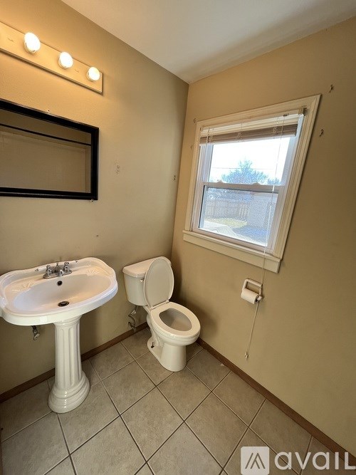 A bathroom with a toilet, sink, and mirror.