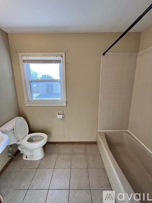 A bathroom with a toilet, tub, and window.