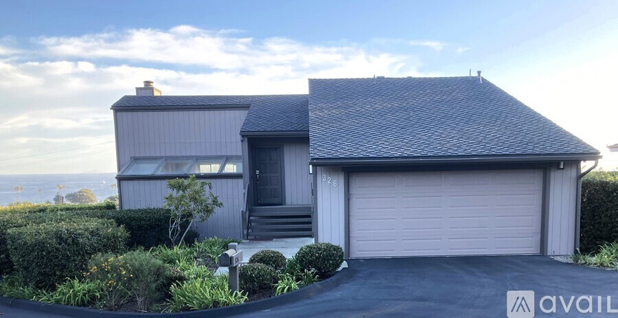 A house with a grey roof and a garage door is for sale.