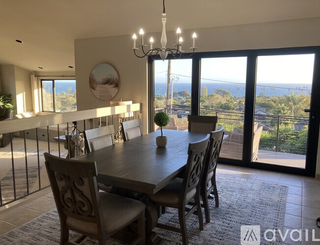 A dining room with a table and chairs and a view of the ocean.
