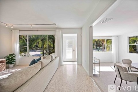 A spacious living room with a long sofa and a glass table.