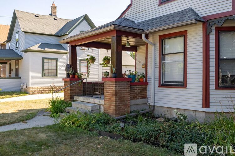 A house with a red and white exterior and a porch with a brick base.