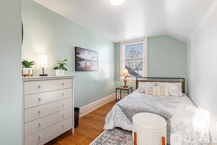 A bedroom with a bed, nightstand, and a dresser with a plant on top.