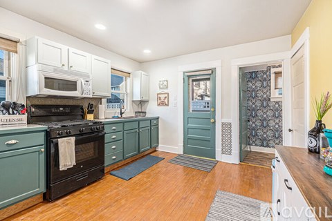 A kitchen with a black stove top oven and teal cabinets.