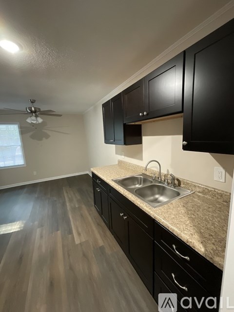 A kitchen with black cabinets and a wooden floor.