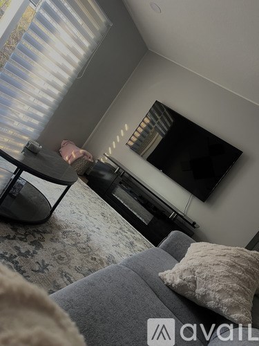 A living room with a grey couch and a television mounted on the wall.